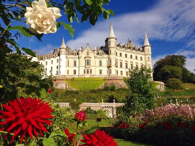 Dunrobin Castle, das sich über einen farbenprächtigen Garten mit auffälligen roten Dahlien und weißen Rosen erhebt.