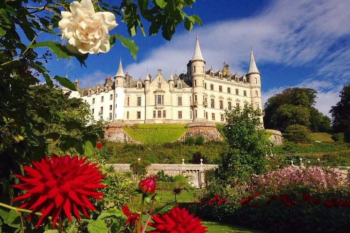 Blick von unten auf Dunrobin Castle, eingerahmt von leuchtenden Blumen im Vordergrund.